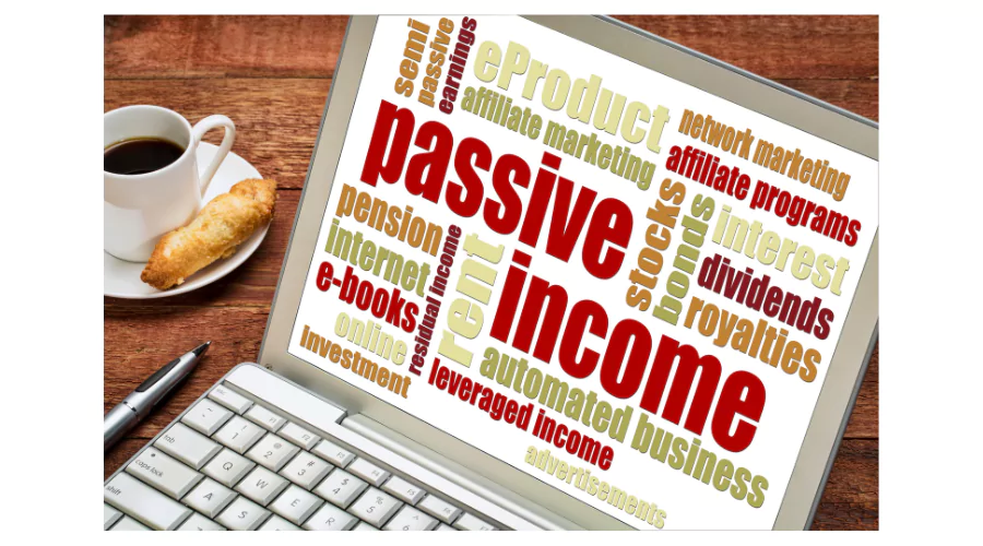 Laptop screen displaying words related to passive income such as 'stocks', 'dividends', 'e-books', and 'affiliate marketing', beside a cup of coffee and pastry, symbolizing the convenience of 'passive income jobs' that can generate earnings alongside regular activities.