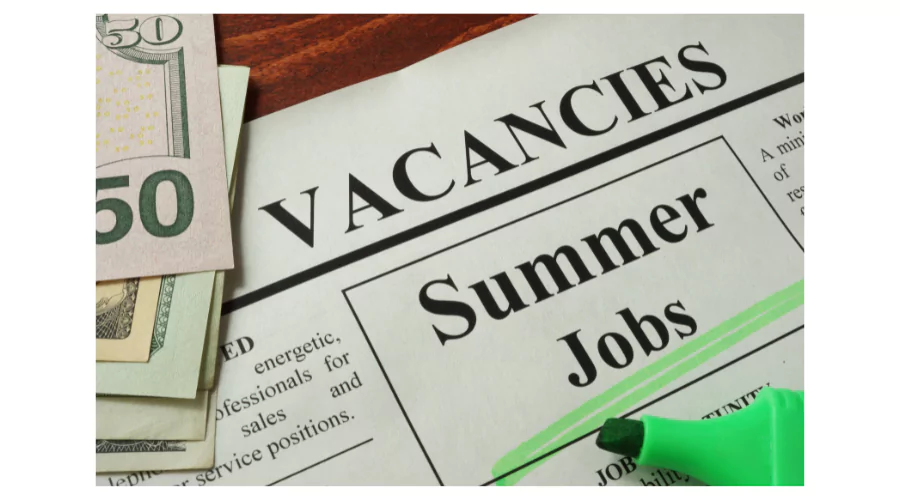 A newspaper clipping highlighting 'Summer Jobs' with a bright green highlighter and U.S. currency on the side, suggests opportunities for summer jobs for teachers seeking seasonal employment.