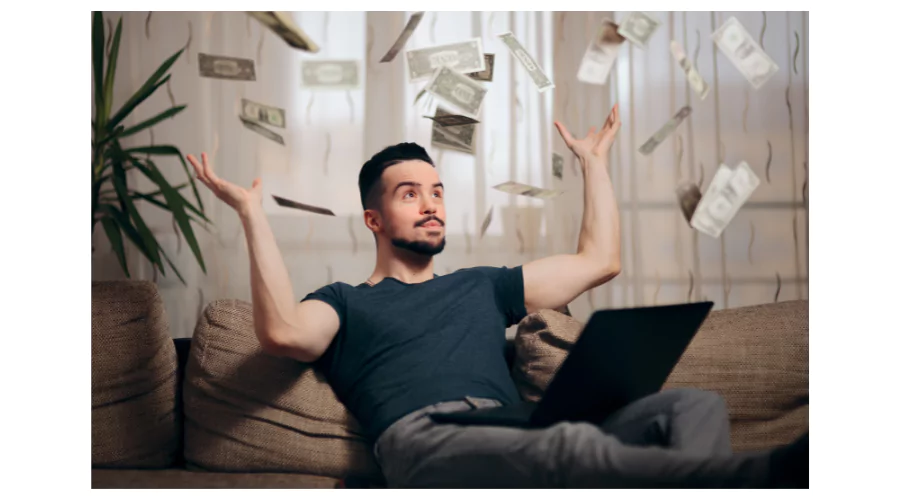 A man lounging on a couch with a laptop, looking surprised as money appears to float down around him, illustrating the potential of discovering secret websites to make money online.